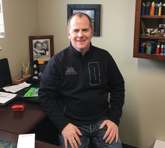 Photo of Dave Huston sitting on his desk.