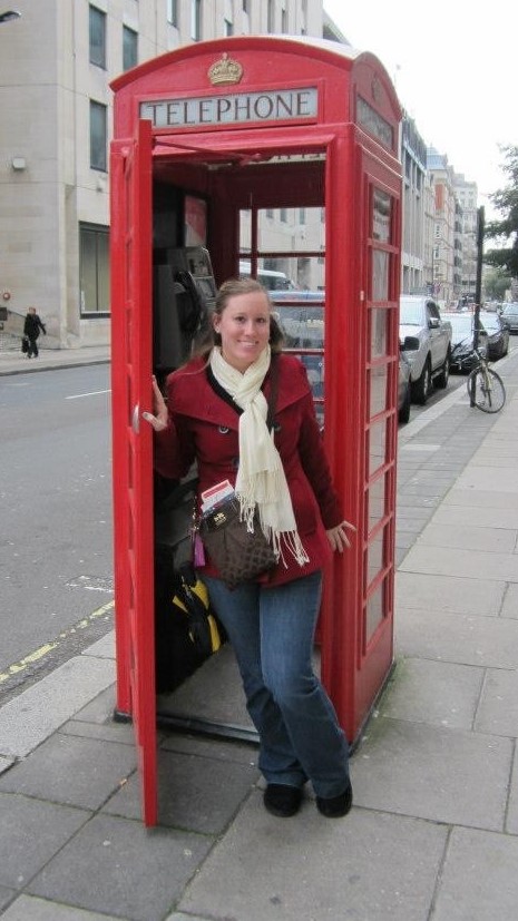 Photo of Kylee Erenberger Koziesek standing in front of a phone booth in New York City